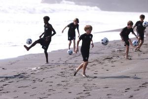 Youth development players of different ages playing soccer in Bali on beach