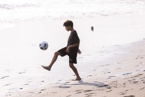 Youth development athlete showing soccer skills on beach in Bali
