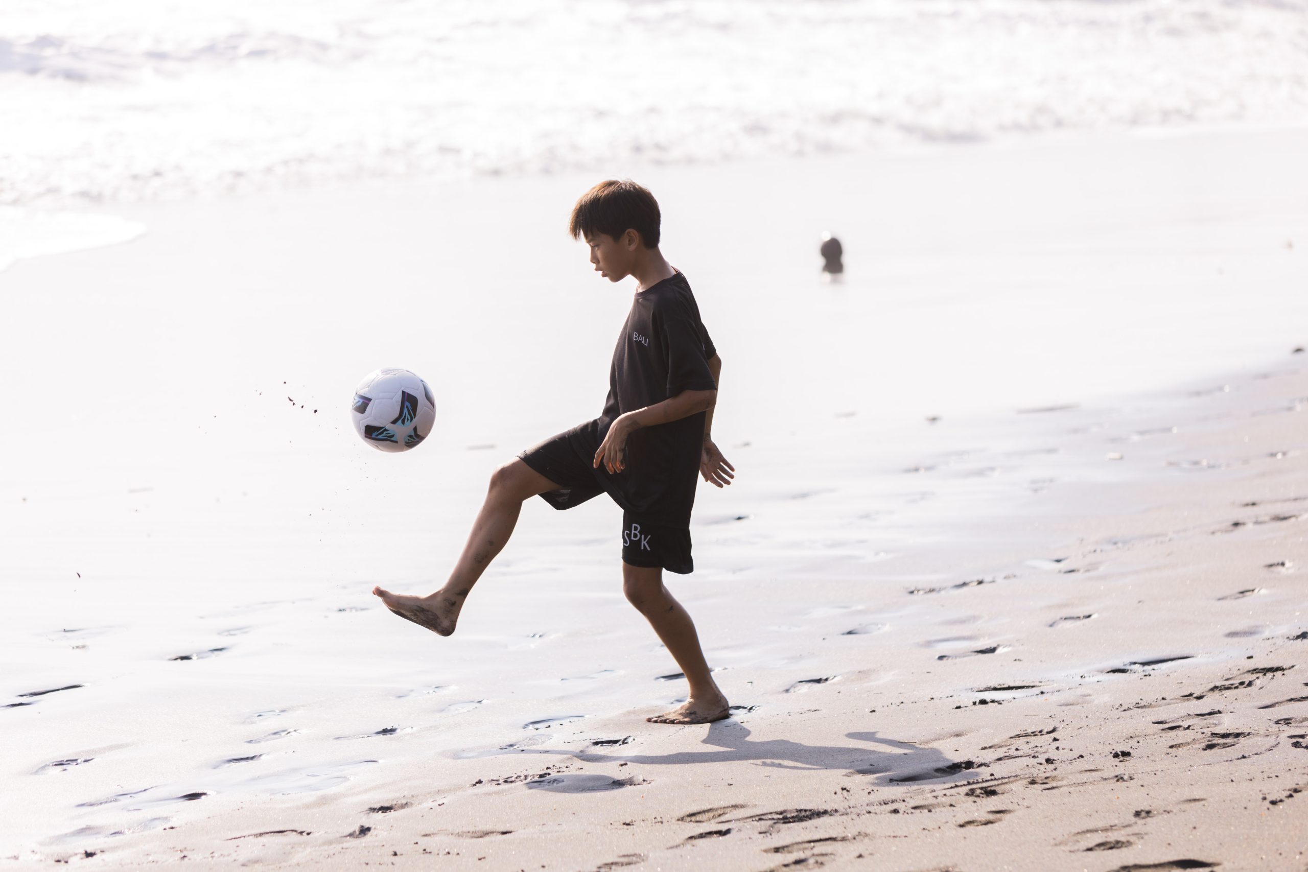 Youth development athlete showing soccer skills on beach in Bali