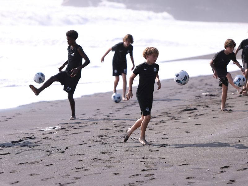 Youth development players of different ages playing soccer in Bali on beach