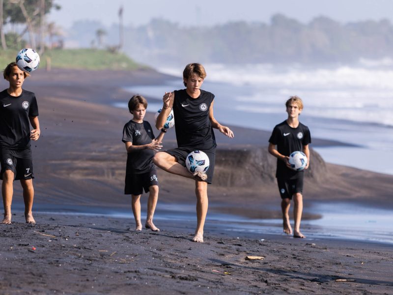 Junior football players practicing football ABCs at Balinese beach