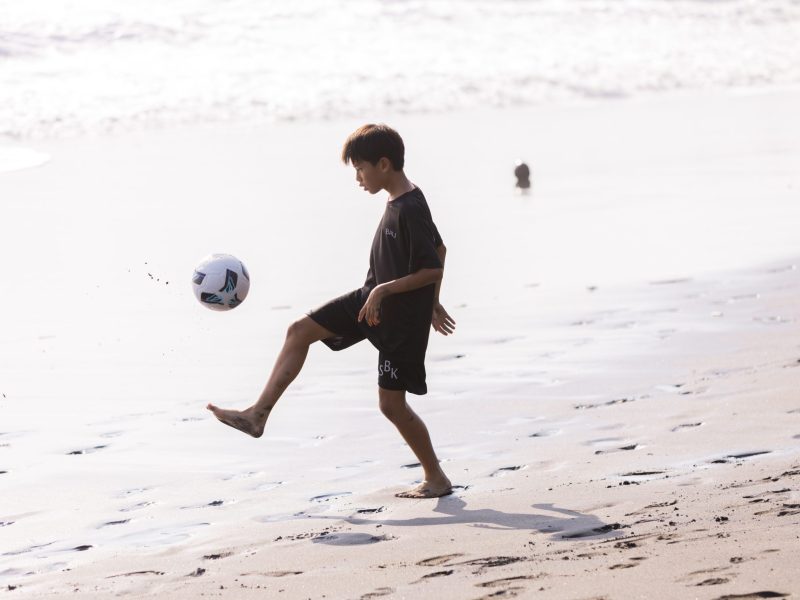 Youth development athlete showing soccer skills on beach in Bali