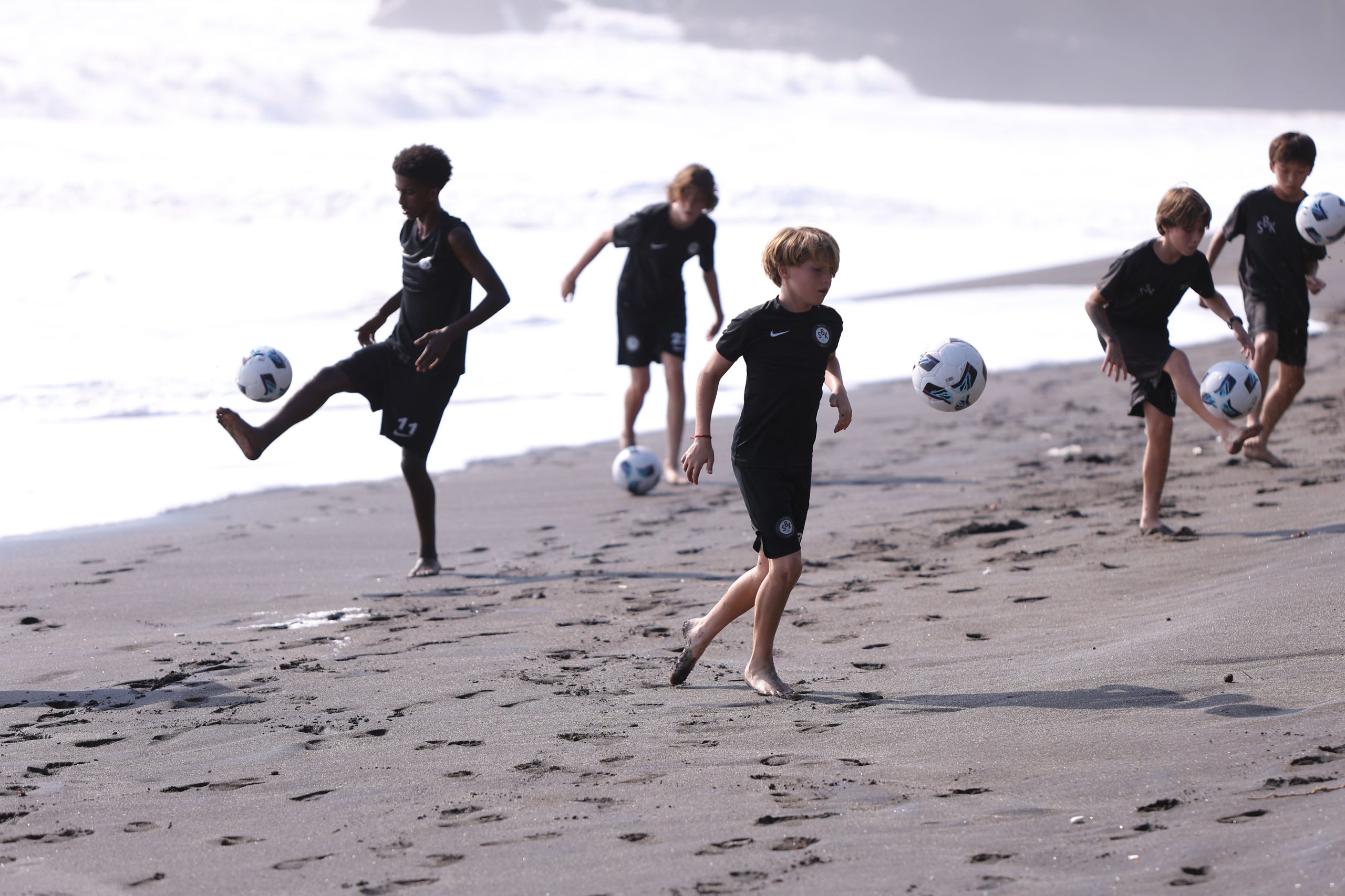 Youth development players of different ages playing soccer in Bali on beach